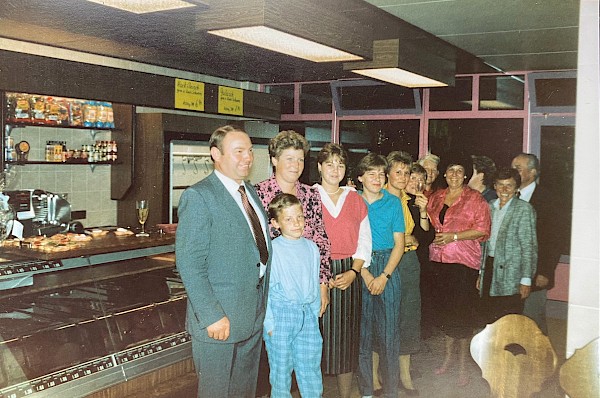 Ein Bild aus alten Zeiten. Friedrich und Marianne Mayer sowie ihre Kinder Bettina und Frank stehen mit weiteren Mitarbeitenden vor der Theke.