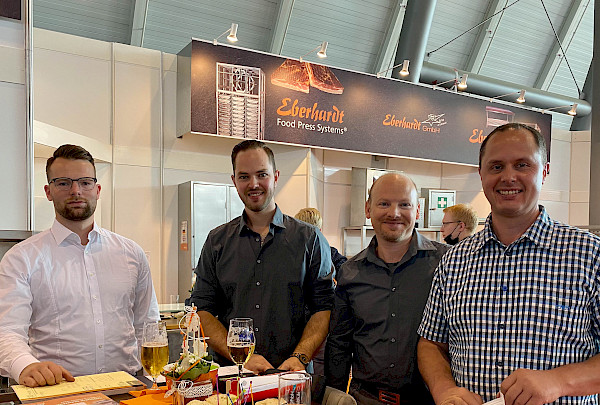 Andreas Fichtel, Frank Mayer, Tobias Fichtel und ein Mitarbeiter der Eberhardt GmbH stehen an einem Tisch und lächen in die Kamera.