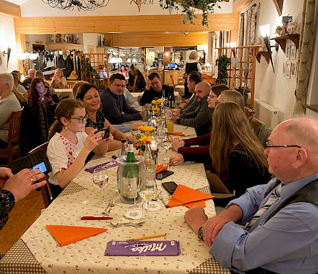 Das Team der Metzgerei Mayer sitzt an einem langen Tisch in einem Restaurant. Vorne rechts im Bild zu sehen Herr Friedrich Mayer.
