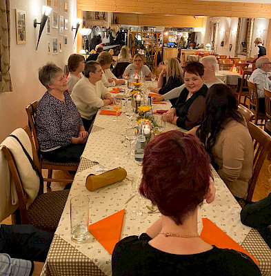 Das Team der Metzgerei Mayer sitzt an einem langen Tisch in einem Restaurant.