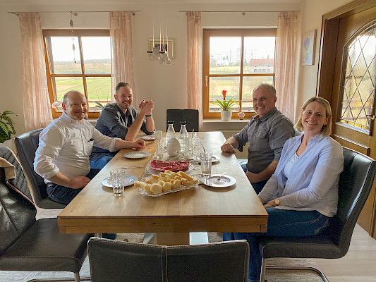 An einem Tisch sitzen Frank Mayer, Tobias Fichtel und Familie Beck. Alle schauen lächelnd in die Kamera.