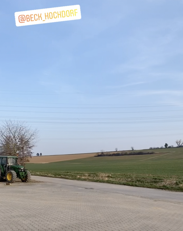 Ein Feld und ein grüner Traktor sind dargestellt.