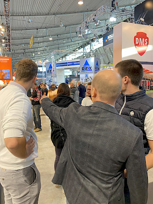 Frank Mayer zeigt auf etwas im Raum der Messe.