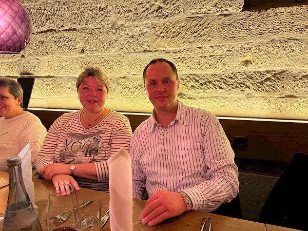 Andreas und Bettina Fichtel sitzen an einem Tisch und lächeln in die Kamera.