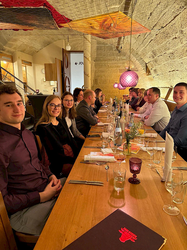 Das Team der Metzgerei Mayer an einem Tisch in einem Gewölbekeller sitzend.