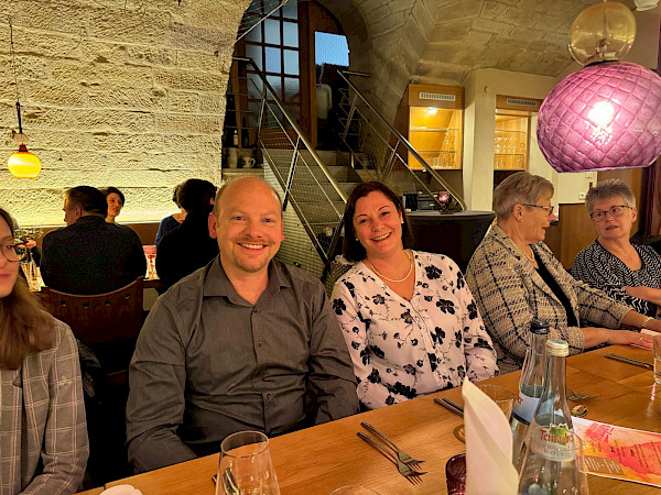 Frank und Ellen Mayer sitzen an einem Tisch und lächeln in die Kamera.