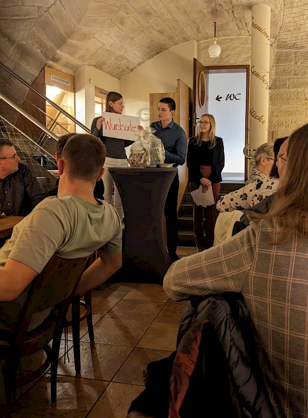 Verena Mayer hebt ein Schild in die Höhe und das Team der Metzgerei Mayer schaut in diese Richtung.