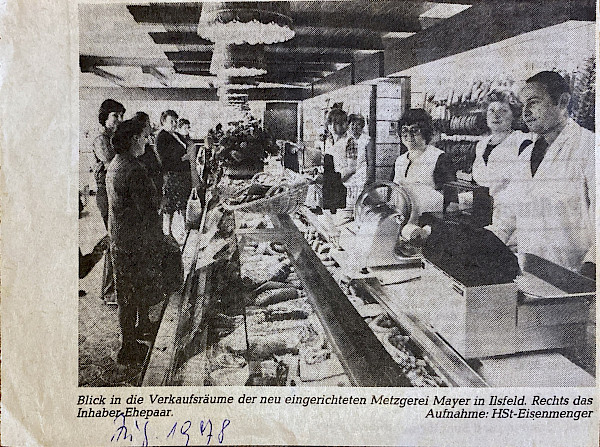 Schwarz weißer Zeitungsausschnitt mit folgender Bildunterschrift: Blick in die Verkaufsräume der neu eingerichteten Metzgerei Mayer in Ilsfeld. Rechts das Inhaber Ehepaar.